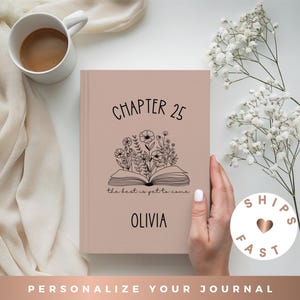 May include: A dusty rose hardcover journal featuring a black line art illustration of an open book with flowers growing from the pages. The text reads CHAPTER 25, the best is yet to come, and the name OLIVIA in a clean, black sans-serif font.