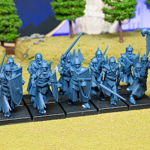 May include: A collection of blue miniature skeleton warriors, equipped with swords and shields, positioned on individual black bases. Some figures carry a banner. The scene is set against a backdrop of miniature trees and a painted landscape.