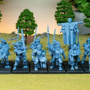 May include: A collection of light blue miniature figurines of soldiers, each standing on a black base. The figures are armed with swords and spears, and some carry a banner. The background features miniature trees and a grassy surface.