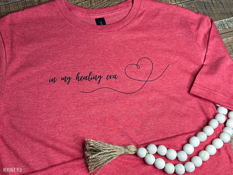 May include: Heather red t-shirt with the text "in my healing eva" and a heart design.