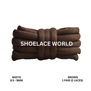 Può includere: Stringhe marroni, larghe 8,5-9 mm, con la scritta "SHOELACE WORLD". L'immagine mostra un paio di stringhe marroni, arrotolate. Le stringhe sono di colore marrone pieno e sembrano essere realizzate con un materiale resistente.