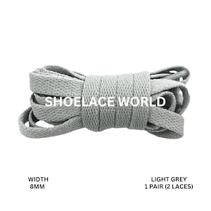 May include: Light grey shoelaces, 8mm wide, in a rolled bundle. The text "SHOELACE WORLD" is printed on the laces. The product is labeled as "LIGHT GREY 1 PAIR (2 LACES)".