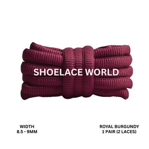 Peut inclure: Une botte de lacets bordeaux royaux, de 8,5 à 9 mm de large, avec le texte "SHOELACE WORLD" en blanc. Les lacets sont d'un rouge-violet profond et sont étroitement enroulés. L'image est sur fond blanc.