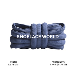 May include: A bundle of faded navy blue shoelaces, approximately 8.5-9mm wide, presented on a white backdrop. The text "SHOELACE WORLD" is printed across the laces. The text "FADED NAVY 1 PAIR (2 LACES)" is also visible.