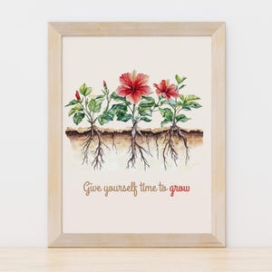 Puede incluir: Impresión artística enmarcada con flores de hibisco rojas, hojas verdes y raíces expuestas. El texto "Give yourself time to grow" está escrito en una fuente cursiva. El marco es de madera clara.