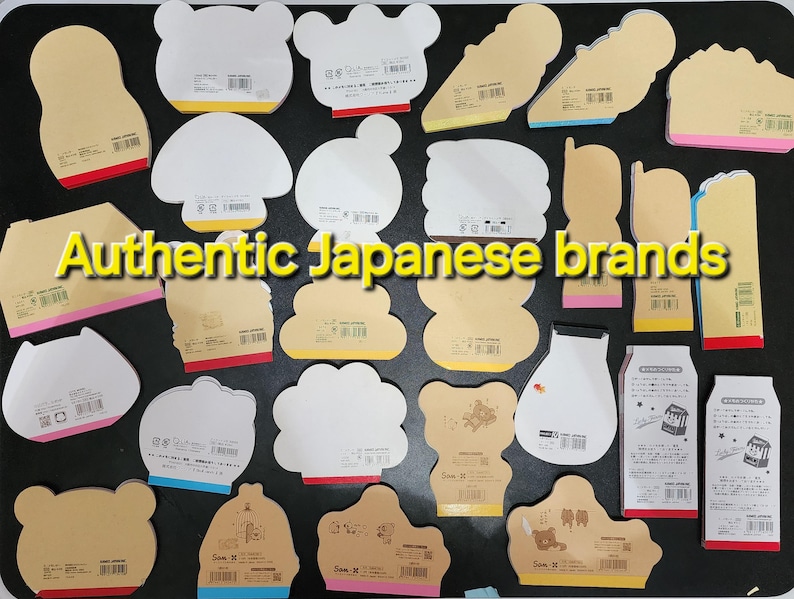May include: A collection of assorted Japanese stationery featuring various designs and colors. The stationery includes memo pads, notepads, and sticky notes. The text "Authentic Japanese brands" is visible in the center of the image.