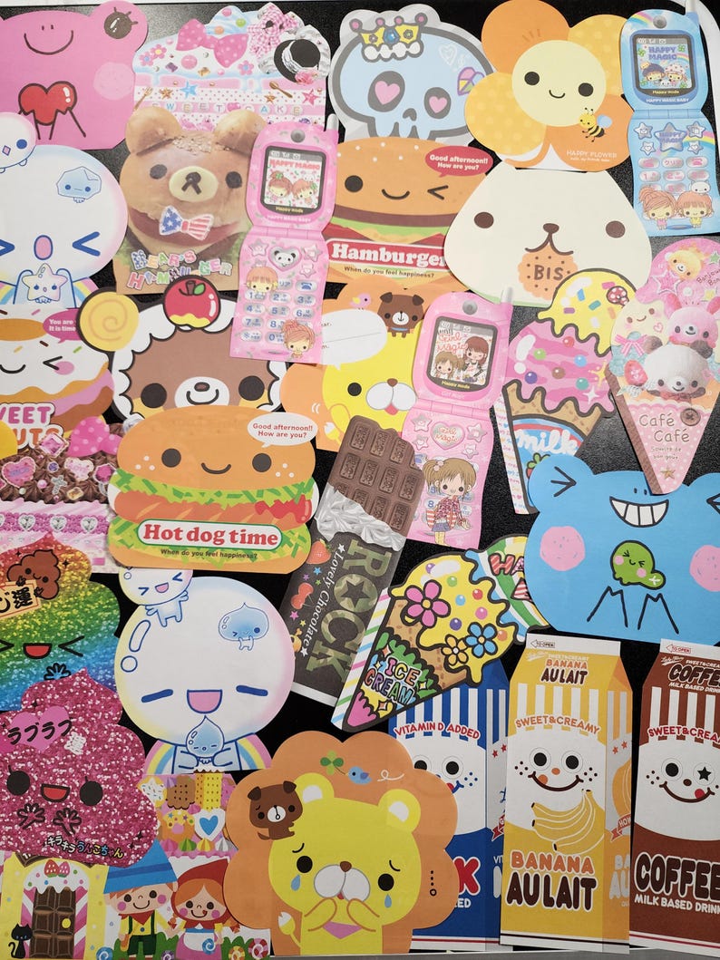 May include: A collection of colorful, cartoon-themed stickers featuring various characters, animals, and food items. The stickers are printed on white paper and have a glossy finish. Some of the stickers have text, such as "Hot dog time", "Banana AULait", and "Coffee".