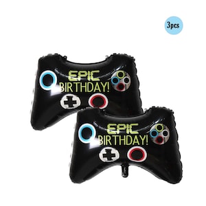 Op de afbeelding: Drie zwarte en witte opblaasbare videogamecontrollers met de tekst "Epic Birthday!" erop gedrukt.
