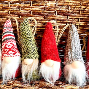 Puede incluir: Seis adornos de gnomos con sombreros de punto de diferentes colores y barbas de piel blanca. Los gnomos est&aacute;n colgados de una cesta de mimbre tejida.