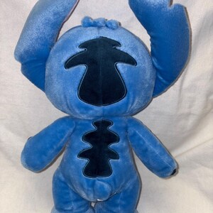 Pu&ograve; includere: Un peluche blu del personaggio Stitch, con grandi orecchie e una toppa blu scuro sul corpo. Il giocattolo ha un'espressione amichevole ed &egrave; realizzato in materiale morbido. Le braccia sono alzate e i piedi sono piccoli e arrotondati.