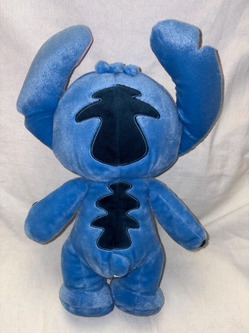 Pu&ograve; includere: Un peluche blu del personaggio Stitch, con grandi orecchie e una toppa blu scuro sul corpo. Il giocattolo ha un'espressione amichevole ed &egrave; realizzato in materiale morbido. Le braccia sono alzate e i piedi sono piccoli e arrotondati.