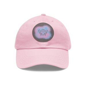 May include: Pink baseball cap with a round, gray patch featuring a cartoon character with antlers and a blue and pink background.