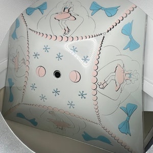 May include: A white ceiling light fixture with a decorative design of girls skipping rope and bows. The light fixture has a white background with pink and blue accents.