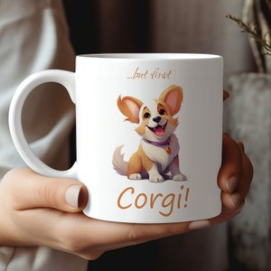 Może przedstawiać: Biały ceramiczny kubek do kawy z kreskówkowym obrazkiem psa rasy corgi. Kubek ma nadrukowany tekst "...but first Corgi!"