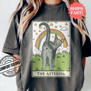 May include: A tarot card with a gray cat with a rainbow behind it. The card is titled "The Asterisk".