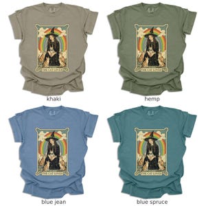 May include: Four different colored t-shirts with a vintage style illustration of a woman in a witch hat surrounded by cats. The text "The Cat Lover" is printed below the image.