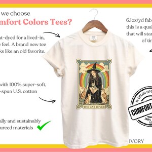 May include: A white t-shirt with a vintage-style illustration of a witch with cats and a rainbow. The text "The Cat Lover" is printed below the illustration. The shirt is made of 100% super-soft, ring-spun U.S. cotton and is available in 14 colors. The text "Comfort Colors" is printed in a circle on the shirt.