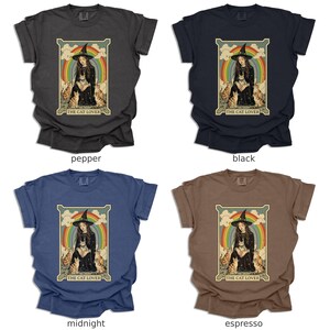 May include: Four different color t-shirts featuring a vintage-style illustration of a woman with a witch hat and cats. The text "The Cat Lover" is printed below the image.