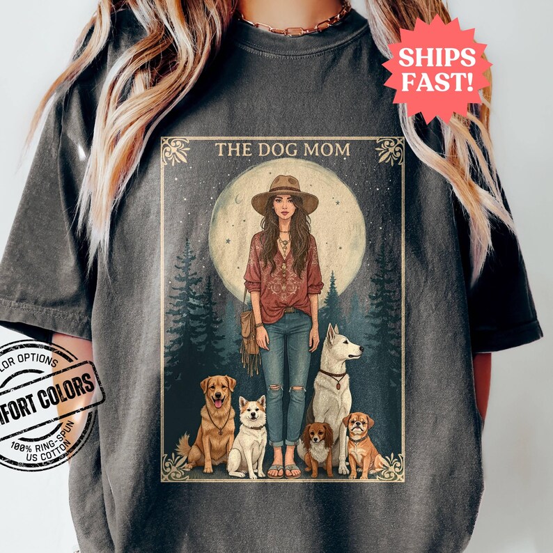 May include: A vintage-style illustration of a woman with long hair and a hat standing in a forest with four dogs. The text "THE DOG MOM" is at the top of the image.