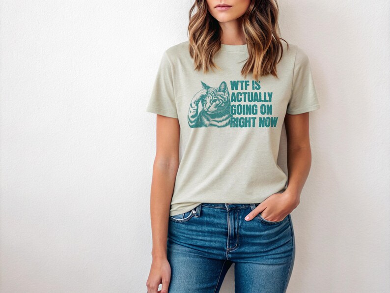 May include: A light green t-shirt with a teal cat graphic and the text "WTF IS ACTUALLY GOING ON RIGHT NOW".