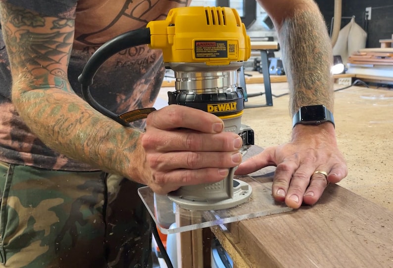 Puede incluir: Una persona usando una fresadora DeWalt amarilla y negra con una gu&iacute;a de pl&aacute;stico transparente para cortar una pieza de madera.