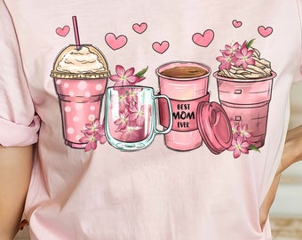 Op de afbeelding: Roze T-shirt met een afbeelding van vier koffiebekers en bloemen. De bekers zijn versierd met roze stippen en harten. De tekst op de koffiebeker is "Best Mom Ever".