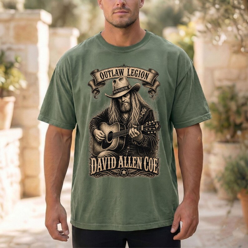 May include: Olive green t-shirt with a graphic of a musician playing a guitar, and the text "OUTLAW LEGION" above and "DAVID ALLEN COE" below. The design is in brown and black.