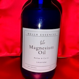 May include: A blue glass bottle with a white label that reads "Bella Essences Magnesium Oil Relax & Calm Lavender 100% Original 4 oz".