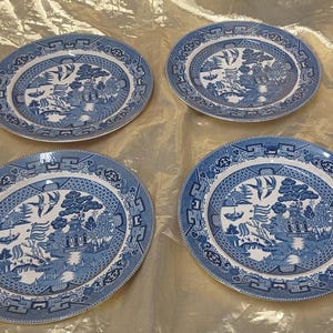 May include: Four blue and white ceramic plates with a traditional Chinese design. The plates have a white background with a blue floral pattern and a blue border.