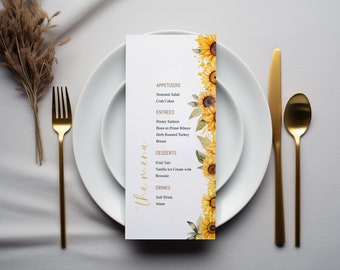 May include: A white menu card with a sunflower design. The menu lists appetizers, entrees, desserts, and drinks. The text on the menu is in gold.