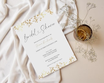 May include: A white invitation card with gold confetti accents and elegant script reading "Bridal Shower." The card includes details for the event, such as the bride's name, date, time, and RSVP information. A decorative floral arrangement sits nearby.