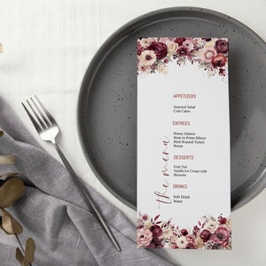 May include: A white menu card with a floral design in shades of pink and burgundy. The menu card lists appetizers, entrees, desserts, and drinks. The text "the menu" is written in cursive.