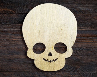 Pode incluir: Um recorte de caveira de madeira com um sorriso simples, perfeito para decorações ou artesanato de Halloween.