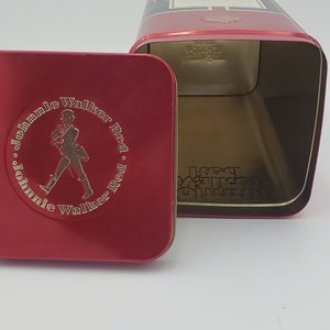 K&ouml;nnte beinhalten: Rote Blechdose mit einem Johnnie Walker Red Label Logo. Die Dose ist ge&ouml;ffnet und der Innenraum ist leer.