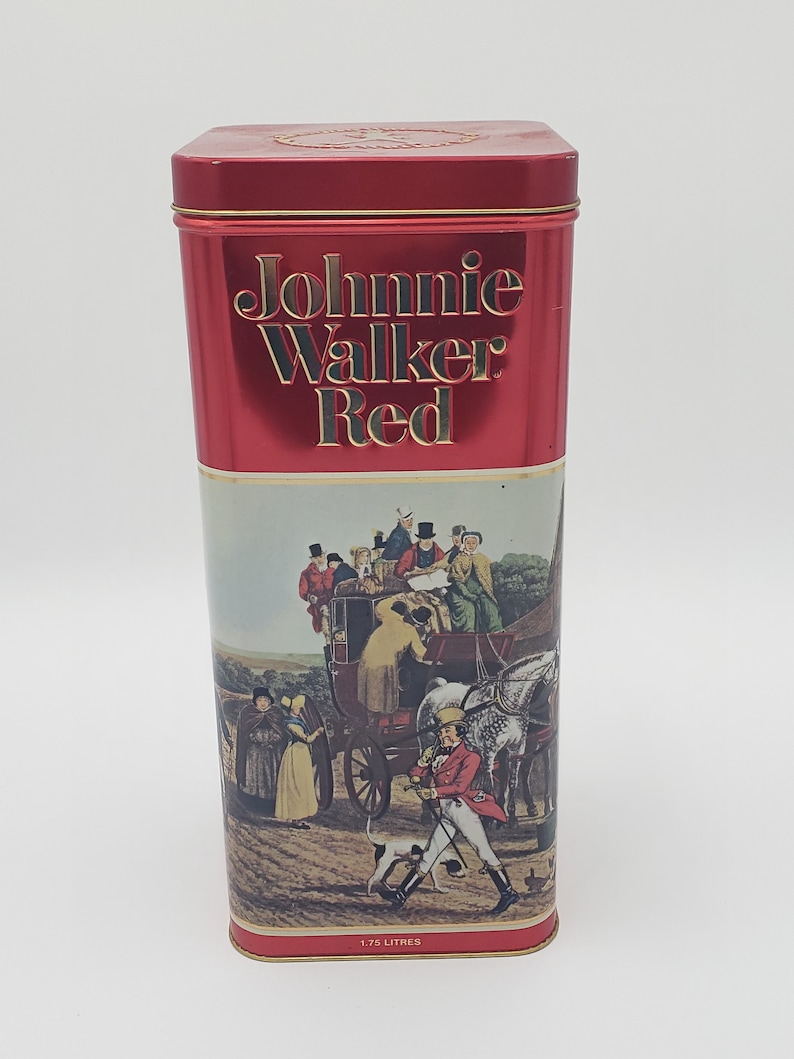 K&ouml;nnte beinhalten: Rote Blechdose mit goldenem Etikett, auf dem "Johnnie Walker Red" steht, und einer Vintage-Illustration einer von Pferden gezogenen Kutsche mit Personen darin. Die Dose hat ein Fassungsverm&ouml;gen von 1,75 Litern.
