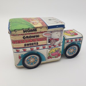 May include: A vintage tin box shaped like a delivery truck with a rabbit driver. The truck is decorated with apples, watermelon, and a pie. The text on the side reads "Home Grown Sweets".
