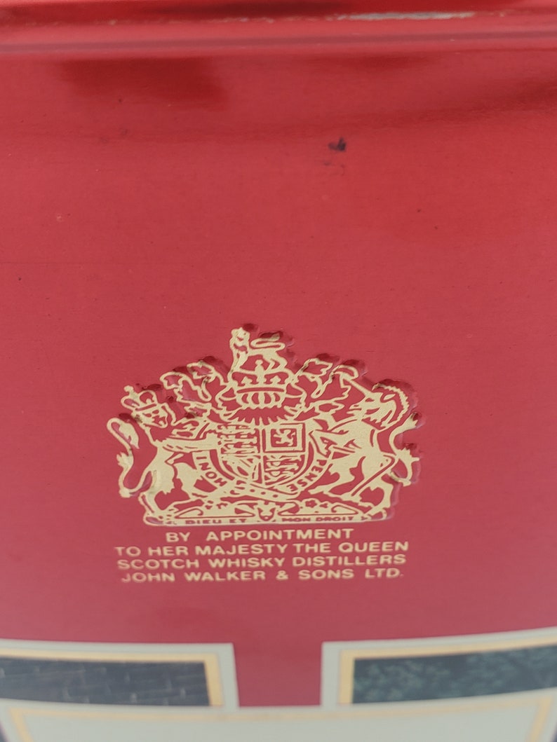 K&ouml;nnte beinhalten: Ein rotes Etikett mit einem goldenen k&ouml;niglichen Wappen und dem Text "By Appointment to Her Majesty The Queen Scotch Whisky Distillers John Walker & Sons Ltd."