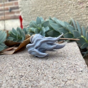 Puede incluir: Un modelo de llama impreso en 3D de color gris, con una superficie texturizada.
