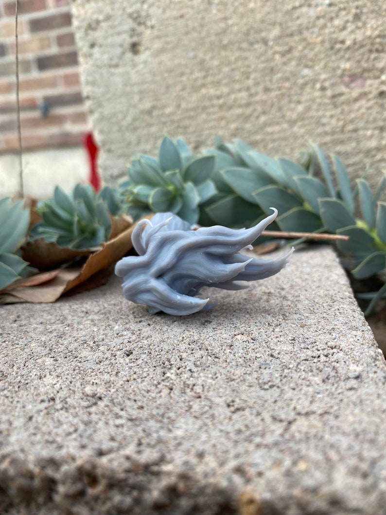 Puede incluir: Un modelo de llama impreso en 3D de color gris, con una superficie texturizada.