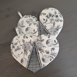 May include: Three black and white floral heart-shaped pot holders with a black and white checkered design in the center.