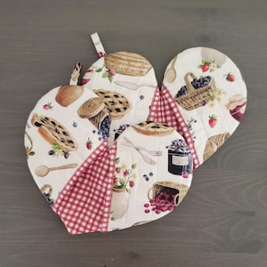 May include: Set of three red and white gingham pot holders with a white background and a pattern of pies, berries, and jars.