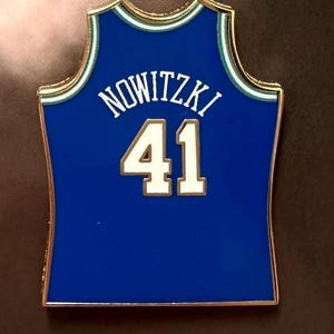 May include: A blue and gold basketball jersey pin with the name "NOWITZKI" and the number "41" on the back.