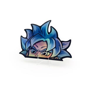 May include: A sticker featuring a stylized illustration of a character with spiky blue hair and intense eyes. The character's face is partially visible, with a determined expression. The sticker is mounted on a clear stand against a white background.