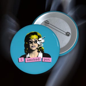 May include: A round, light blue button with a pop art style image of a woman wearing pixelated sunglasses and smoking. The text "I smoked pot" is displayed in pink boxes below the image. A second button is visible.