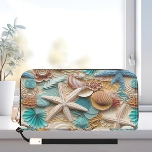 May include: A zippered wallet featuring a beach-themed design with starfish, seashells, and wave-like patterns in shades of beige, blue, and brown. The wallet has a black wrist strap and gold-colored zipper.