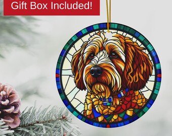 May include: Round Christmas ornament featuring a dog's face in a stained-glass style. The dog has brown and tan fur, a black nose, and is wearing a blue collar. The ornament has a gold string for hanging and the text "Gift Box Included!"