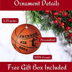 May include: A round ceramic basketball ornament, 3.25 inches in diameter, with personalized text and a silhouette of a basketball player. The ornament is orange with black lines and text. The text includes the name "JACKSON", the number "12", and the year "2024".