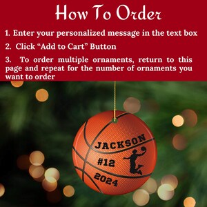 May include: A round basketball ornament with the name "JACKSON", the number "12", and the year "2024" printed on it. The ornament has a basketball design and a silhouette of a basketball player. The ornament hangs from a gold string.
