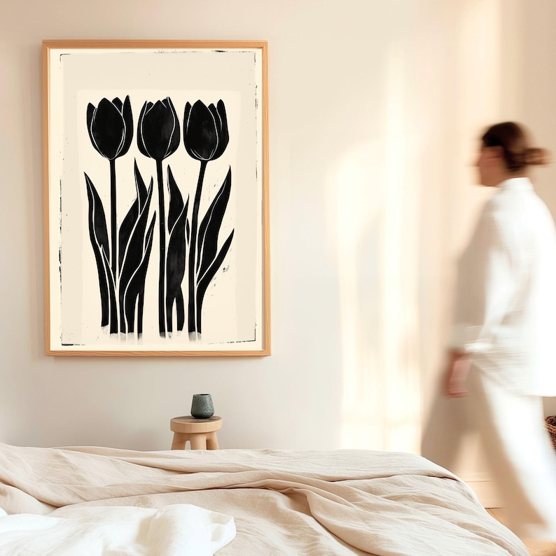 May include: A framed art print featuring three black tulip silhouettes against a cream background. The artwork is in a natural wood frame, creating a minimalist and modern aesthetic. The image is in a bedroom setting.