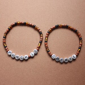 May include: Two beaded bracelets with brown and black beads. One bracelet says "Punch It" and the other says "Chewie".